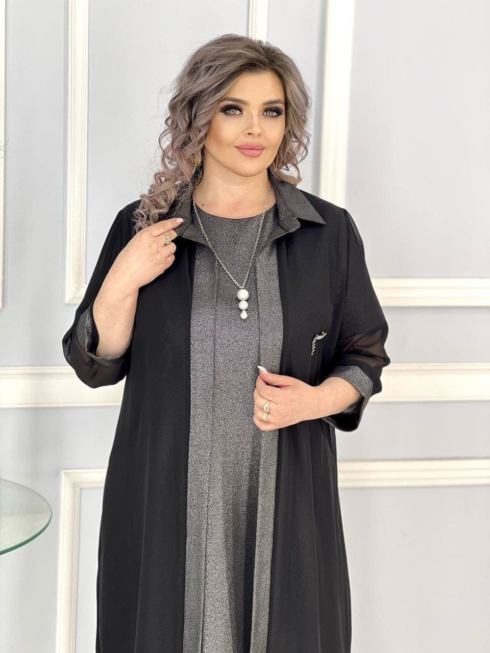 სვოროვსკის ნაქსოვი ტანსაცმლით შეკერილი კაბა შიფონის კონცხით, მოდელი ელვარებს მუქი ქურთუკში და ატარებს დიდი ფორმის ძვირფასეულობას.