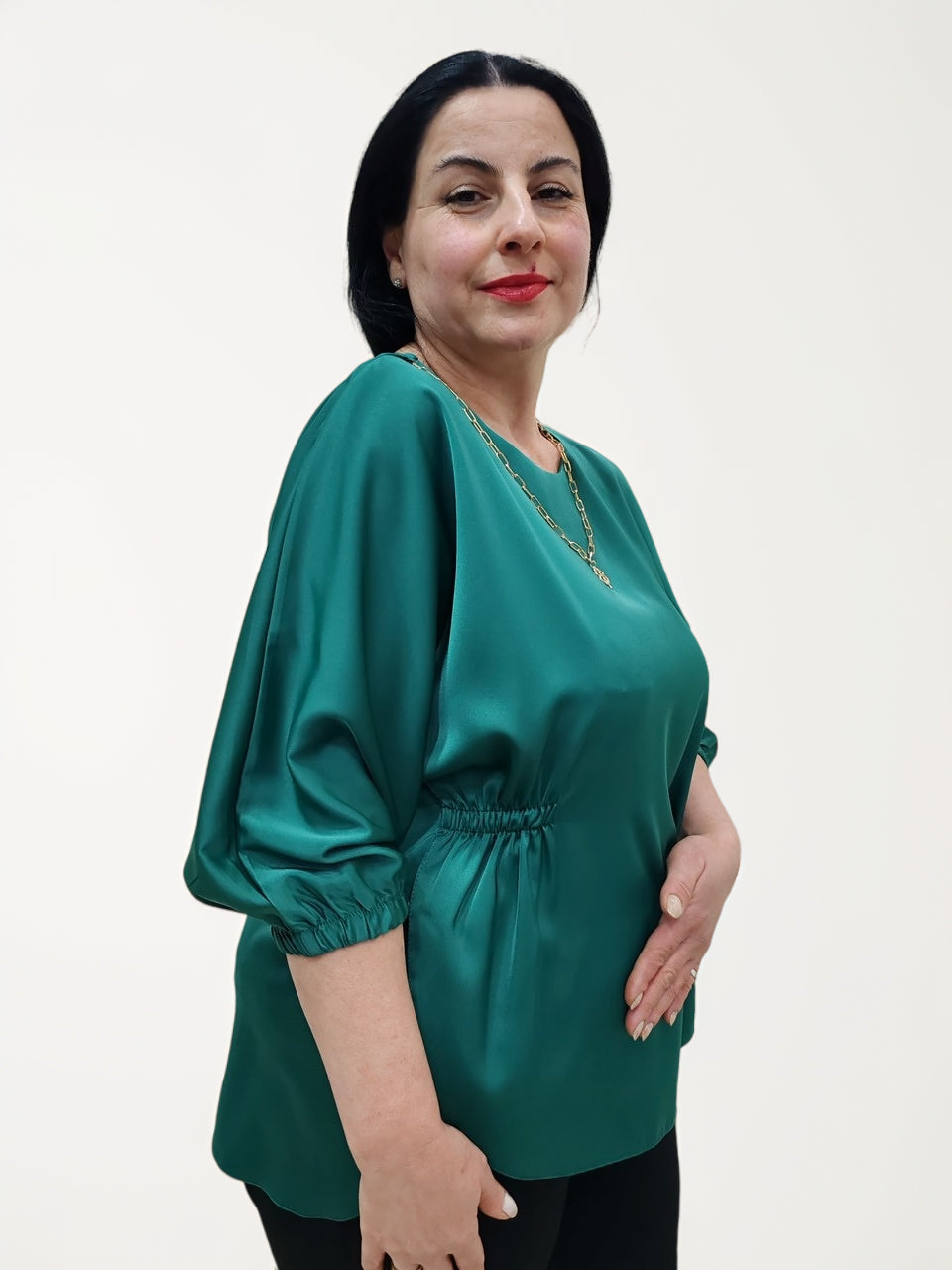 წაგრძელებული დეკორაციის ბლუზა რუსთავში - ქალბატონი მწვანე ბლუზაში, მხარსა და მხრების ხაზზე გამშვენებული დეტალებით.