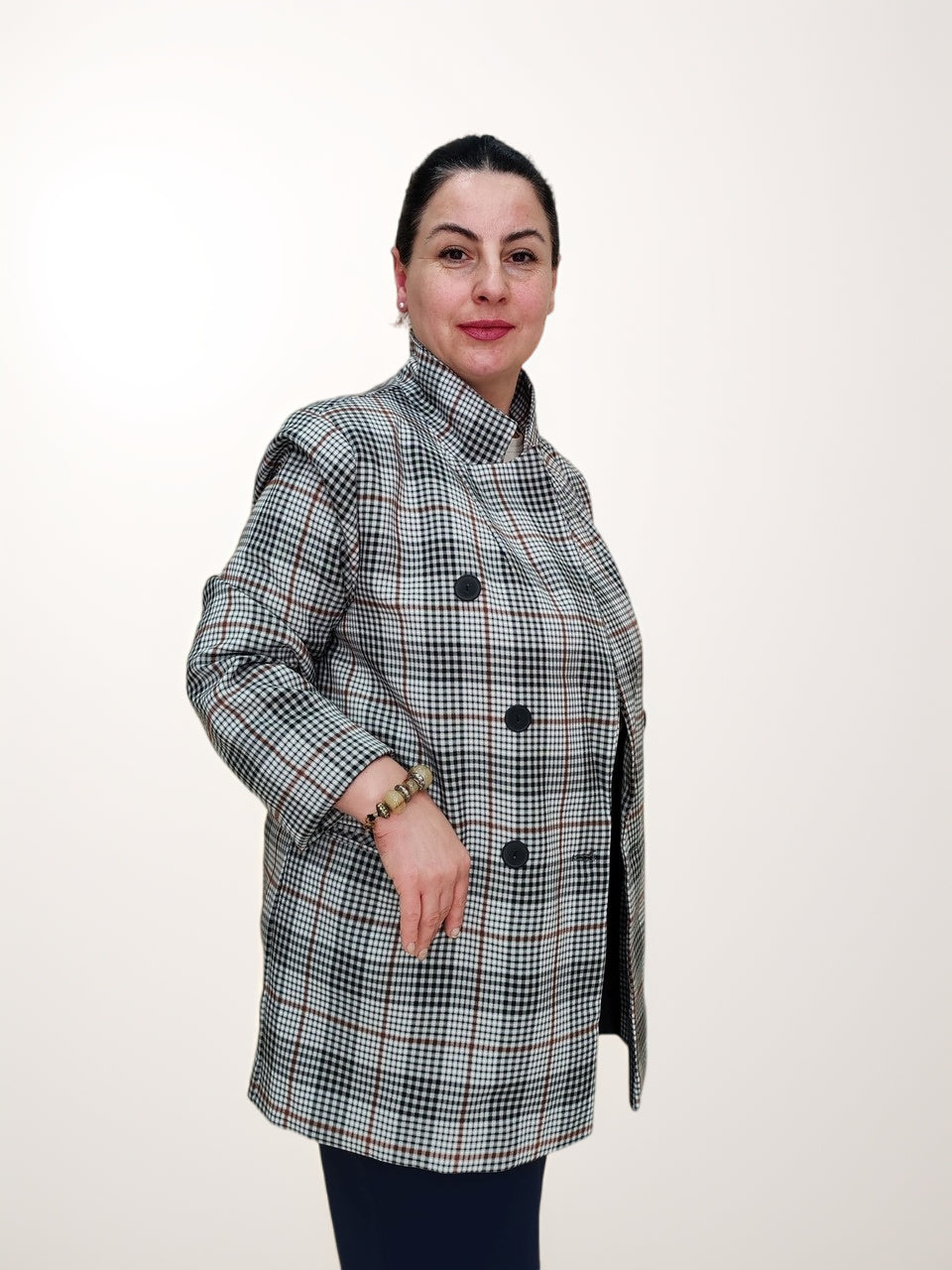 ქალთა პიჯაკი ბარბის პრინტით საქართველოში, მოდელი გვერდიდან პოზირებს, ღია ღილებით პიჯაკით, რომელიც ჭარბად დიზაინის ელემენტებს აერთიანებს.