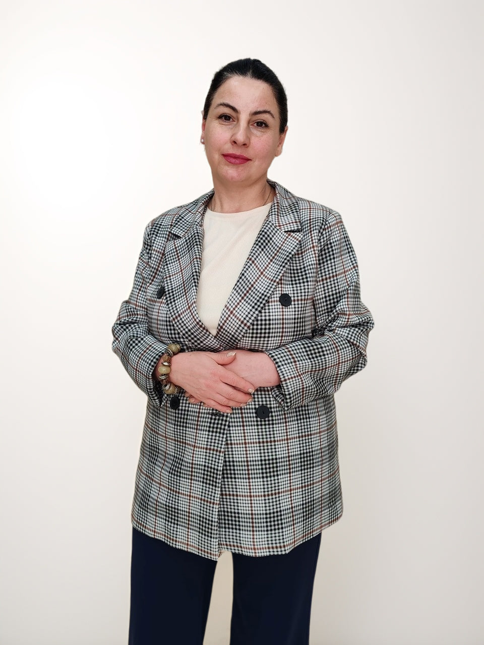 ქალთა პიჯაკი ბარბის პრინტით საქართველოში, მოდელი აცვია ორმაგი ხოფერით შემოსილი პიჯაკი, რომელიც გაწვდილია მინიმალისტურ ფონზე.