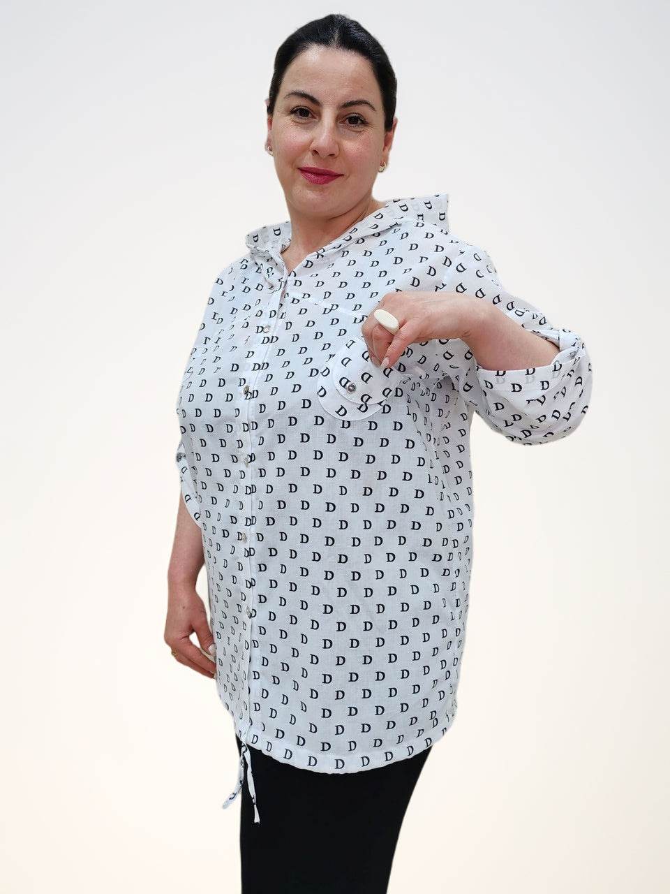 Блузка - ბამბის ბლუზა თავსახურით, model presenting a white shirt with D letter pattern, highlighting the front.