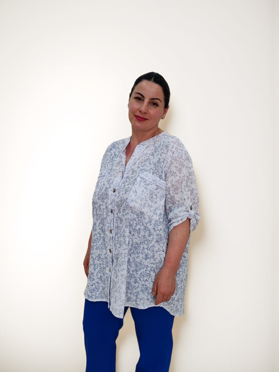 ბამბის ბლუზა გულმკერდის ჯიბით პლუს ზომა, ქალი, რომელიც პოზირებს და ჯიბის დეტალებს ასახავს.