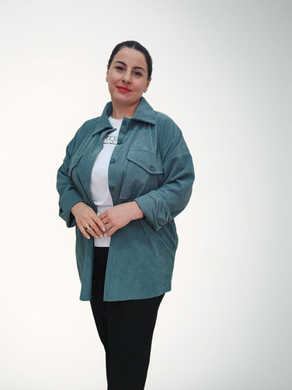ქალის პერანგი დიდი ზომის რუსთავში, მოდელი აცვია მწვანე რბილი ქსოვილის პერანგი, პოზა მარჯვენა ხელით სახეზე.