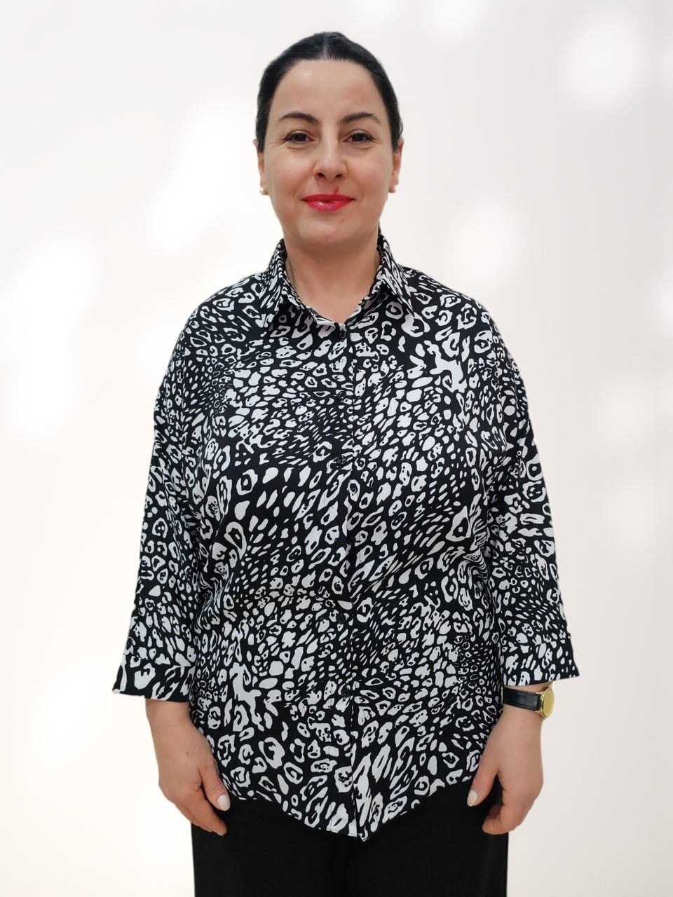 ბლუზის პერანგი ინგლისური საყელოთი ცხოველური პრინტით, ქალის მოდელი, რომელიც უყურებს კამერას და აცვია შავი და თეთრი ბლუზა.