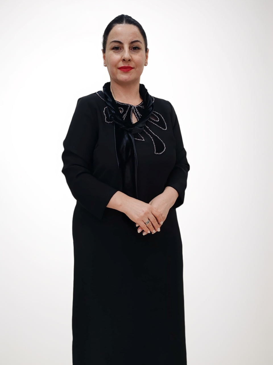შავი კაბა მბზინავი ყვავილოვანი დეკოლტეთ, მოდელი პოზნებაა, გრძელი ხელების დიზაინით.