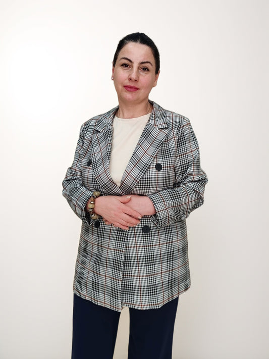 ქალთა პიჯაკი ბარბის პრინტით საქართველოში, მოდელი აცვია ორმაგი ხოფერით შემოსილი პიჯაკი, რომელიც გაწვდილია მინიმალისტურ ფონზე.