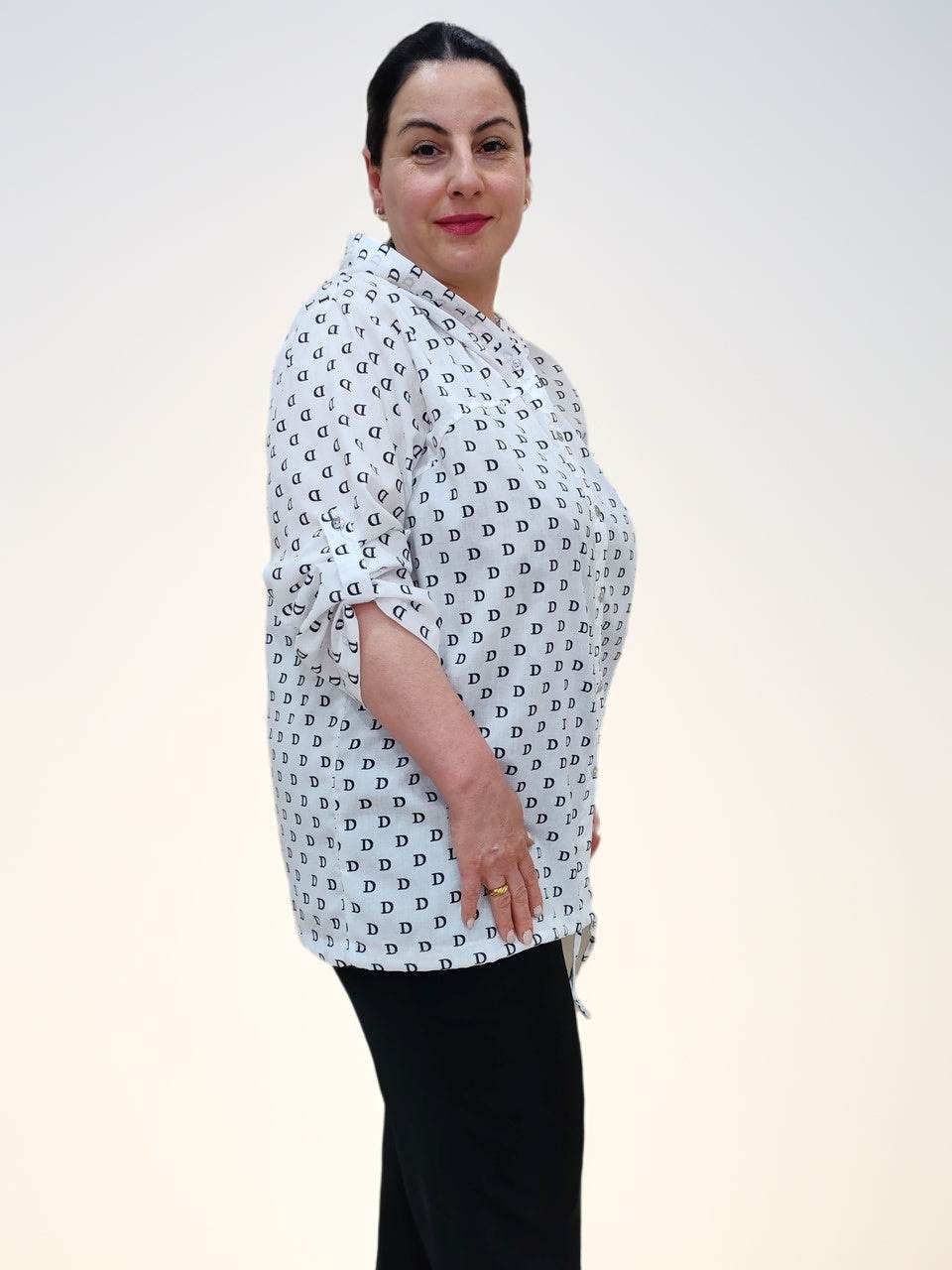 Блузка - ბამბის ბლუზა თავსახურით, side view of a white shirt with D letter pattern, model posing elegantly.