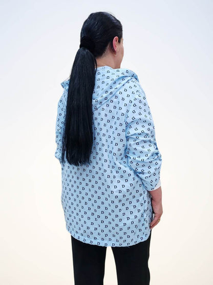 Блузка - ბამბის ბლუზა თავსახურით, showcasing back view of a light blue shirt with D letter pattern, model with long hair.